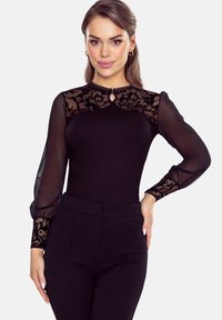 Czarny bodysuit z długimi przezroczystymi rękawami ozdobionymi koronką w kwiaty, okrągłym dekoltem i małym detalem w kształcie dziurki. Gładka tekstura materiału.