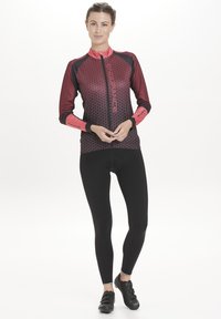 Long-sleeve cycling jersey in dark red and black with hexagonal pattern, full zipper, and black leggings paired with black cycling shoes.