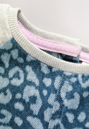 Sweatshirt en denim bleu avec un motif léopard, col côtelé gris et couture intérieure rose en accent. Tissu tissé texturé.