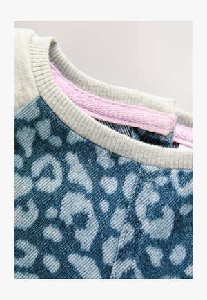 Felpa in denim blu con motivo leopardato, colletto grigio a costine e cuciture interne rosa come dettaglio. Tessuto intrecciato strutturato.