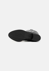 Schwarzer Lederschuh mit einer strukturierten Sohle. Verfügt über eine abgerundete Spitze und minimale Details. Die Sohle zeigt ein eingeprägtes Branding und Größenmarkierung.
