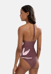 Brązowy jednoczęściowy strój kąpielowy z różowym haftem w kwiaty, wysoka nogawka i projekt na halter. Wykonany z gładkiego, elastycznego materiału.