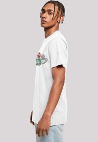 White t-shirt with short sleeves featuring a colorful graphic design with text and coffee cup illustration. Simple cotton texture and fit.