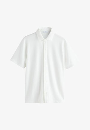 Biela košeľa s krátkymi rukávmi, ktorá má rebrovanú textúru, zapínanie na gombíky a klasický golier. Čistý dizajn bez viditeľných vzorov alebo ozdôb.