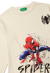 Beżowa bluza z kolorowym grafiką Spider-Mana z efektem rozprysku. Gładka tekstura, okrągły dekolt oraz kontrastowe czarne logo pająka.