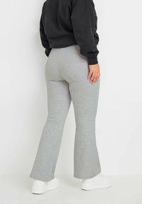 Grå vida sweatpants i mjuk bomullsmix med midjehögt band. Bärs med en svart kortad sweatshirt och vita sneakers.