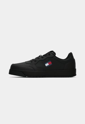 Sort syntetisk sneakers med flad sål, rund tå og struktureret overflade. Har et lille logo patch i rød, hvid og blå på siden.