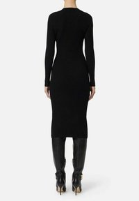 Abito nero in maglia a costine con maniche lunghe, design aderente, lunghezza al ginocchio, abbinato a stivaletti neri con tacco a spillo al ginocchio.