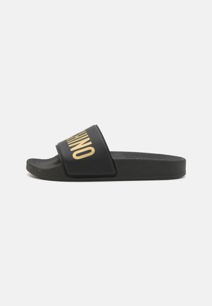 Svart sandaler med glatt såle i gummi, bred stropp med gullbokstaver.Minimalistisk design med flat profil.