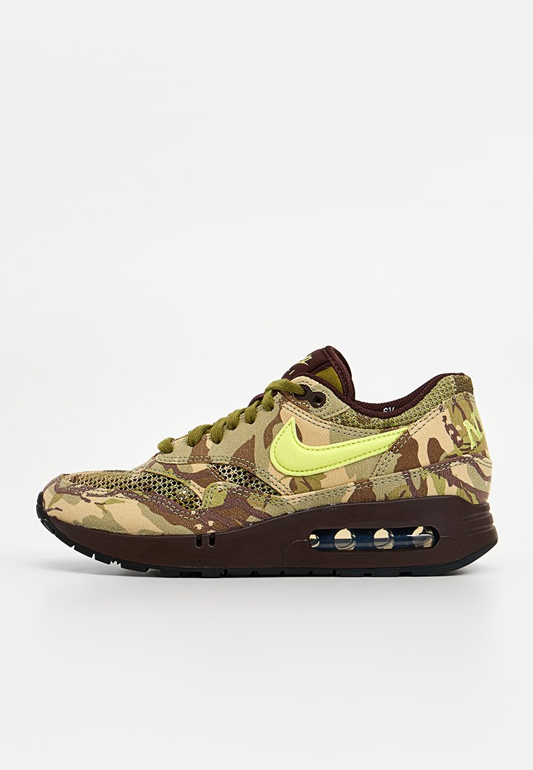 Zapatilla Nike de camuflaje en tonos marrón, verde y beige. Presenta un logo amarillo, paneles de malla y amortiguación Air en la suela.