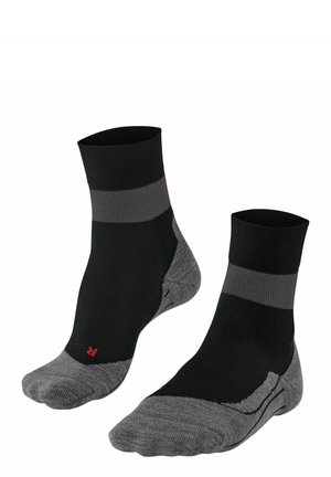 Chaussettes de cheville noires et grises avec texture côtelée, présentant une rayure grise et une zone de renforcement au niveau des orteils. Détail du logo rouge sur le côté.
