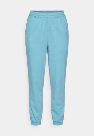 Light blue sweatpants made of soft, textured fabric, featuring an elastic waistband and cuffs, with a relaxed fit and tapered legs.