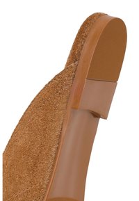 Gros plan de la semelle d'une chaussure en daim marron montrant un talon texturé et une semelle intermédiaire lisse avec une couture détaillée le long du bord.