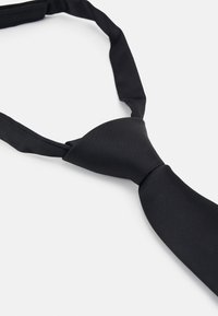 Noeud papillon en tissu lisse, présentant un design classique avec une forme étroite et un centre noué, adapté aux occasions formelles.