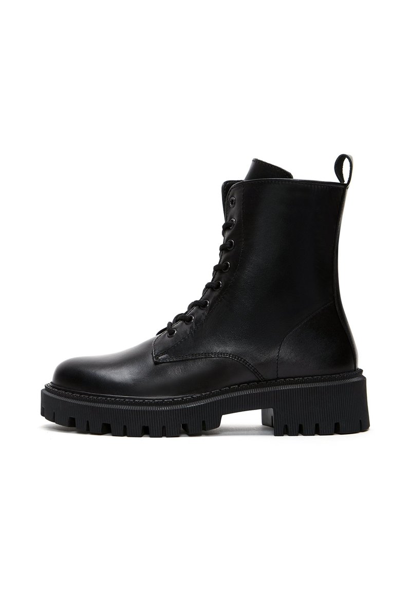 Bottes noires en cuir à la cheville avec un devant lacé, bout rond et semelle en caoutchouc épaisse avec des ridges texturées. Comprend une languette à l'arrière.