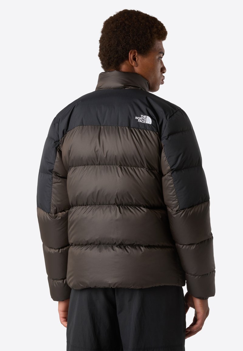 Schwarze und dunkelgraue Mütze mit hohem Kragen, gestepptem Design und einem Logo auf dem oberen Rücken. Glattes, wasserabweisendes Material.