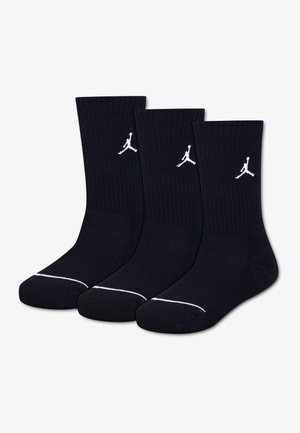 Τρεις μαύρες κάλτσες Crew με λευκά λογότυπα Jumpman στις μανσέτες και λευκές ρίγες κοντά στα δάχτυλα, τοποθετημένες δίπλα-δίπλα.