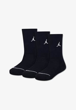 Τρεις μαύρες κάλτσες Crew με λευκά λογότυπα Jumpman στις μανσέτες και λευκές ρίγες κοντά στα δάχτυλα, τοποθετημένες δίπλα-δίπλα.