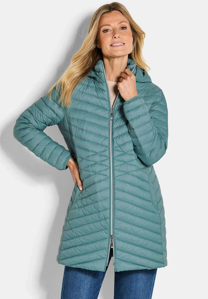 Gequiltede teal pufferjas met een rits aan de voorkant, capuchon en zijzakken. Heeft een middellange ontwerp en diagonale stikpatronen voor isolatie.