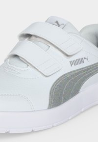 Λευκό αθλητικό παπούτσι Puma με δύο λουράκια velcro, ριγέ διακοσμημένη ασημί ρίγα Puma και επενδυμένη γλώσσα με το λογότυπο Puma.