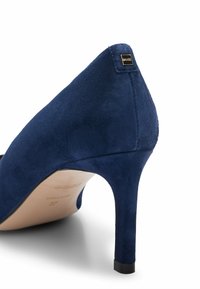 Pompe à talon aiguille en suède bleu marine avec un talon fin et une petite plaque en or portant le logo "BOSS" près du sommet du talon.