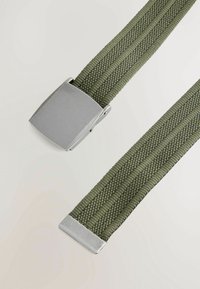 Zelený pletený pásek s plochou stříbrnou kovovou sponou, která má texturovaný design a dvě kovové konce pro bezpečné nošení.