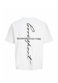 Biele tričko s krátkym rukávom s čiernym zvislým kurzívnym nápisom „Conscious“ a vodorovným textom „Worldwide Since ©1990“ na zadnej strane.