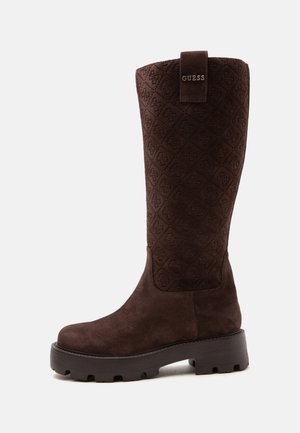 Bottes hautes en daim marron avec tige matelassée à motif et semelle épaisse en caoutchouc, dotées d'une languette avec logo Guess en haut.