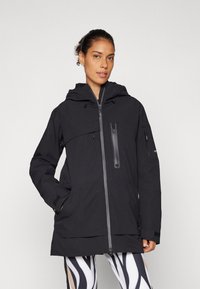 Black waterproof jacket with a hood, front zipper, chest and side pockets, elastic cuffs, and a tunic length. Smooth, matte texture.