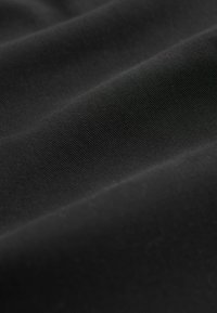 Black fabric featuring a smooth texture with fine diagonal ribs. The material appears soft and pliable, with consistent shading throughout.
