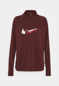 Bordeauxfarbener Nike-Pullover mit Reißverschluss bis zur Hälfte des Halses, langen Ärmeln und einem großen weißen und roten Logo auf der Brust, aus einem glatten, leichten Material.