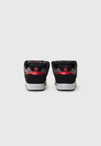 Pair of black, gray, and red DC brand sneakers shown from the back, with white soles on a plain white background.