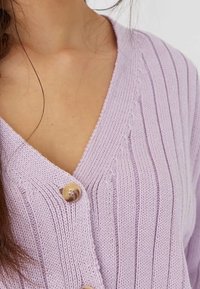 Cardigan en tricot lavande avec une texture côtelée, présentant un col en V et une fermeture à boutons en bois, mettant en valeur des rayures verticales.