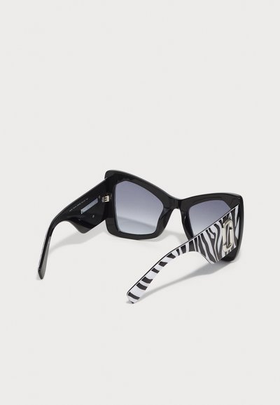 Zwarte oversized zonnebril met getinte glazen en een zebra-gestreepte arm; beschikt over een hoekig frameontwerp en zilveren accenten op de slapen.
