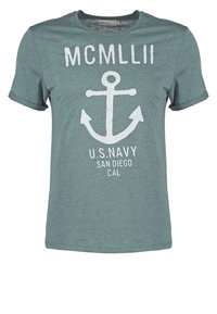 Light teal short-sleeved t-shirt featuring white anchor graphic and text "MCMLLII U.S. NAVY SAN DIEGO CAL." Soft, textured fabric.
