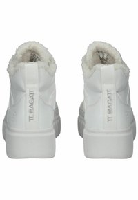 Zapatillas altas blancas con un forro de pelo blanco y suave en el cuello, marca en relieve y una suela de goma gruesa con textura estriada.