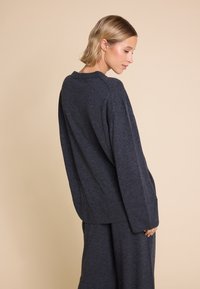Mørkegrå oversized genser laget av mykt stoff, med rund hals, lange ermer og avslappet passform, sammen med matchende underdeler.