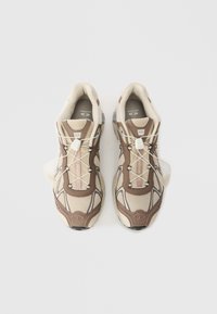 Bež i smeđe atletike cipele s gornjim dijelom od teksturirane mreže, s elegantnim dizajnom, elastičnim vezicama i podstavljenom potplatom.
