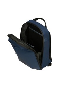 Zaino blu navy con un esterno testurizzato, cerniere nere e un compartimento aperto che rivela una tasca in rete e una sezione imbottita per dispositivi.