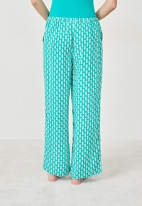 Pantalons larges turquoise avec un motif floral blanc, dotés d'une taille élastique confortable et de poches latérales. Tissu doux et léger.