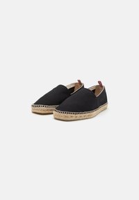 Espadrillas in tela nera con suola in corda di juta, punta a forma di mandorla e dettagli a strisce rosse e blu sui tiranti al tallone.