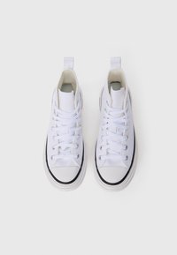Scarpe sneakers alte in tela bianca, con lacci bianchi piatti, suole in gomma nera e un tassello sul retro.