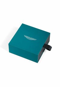 Boîte bleu sarcelle à finition lisse, ornée d'un logo Aston Martin métallique sur le couvercle et d'une languette en tissu noir sur le côté.