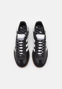 Pair of black Adidas Samba sneakers with white stripes, laces, and branding, shown from above on a plain white background.