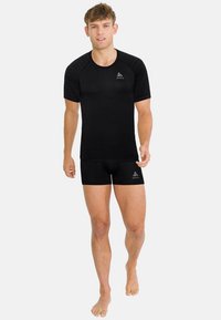 Zwarte atletische T-shirt met korte mouwen en gestructureerd patroon; gecombineerd met zwarte shorts. Gemaakt van flexibele stof die is ontworpen voor comfort en prestaties.