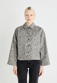 Veste imprimée léopard en tissu doux, dotée d'un col, d'une fermeture à boutons et de deux poches poitrine. Scénario de couleurs gris et noir.
