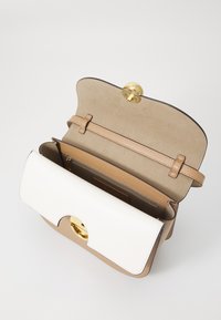 Sac à main en cuir beige et blanc avec un fermoir doré, offrant un intérieur spacieux et une texture lisse. Agrémenté d'une fine bandoulière.