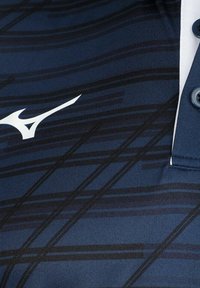 Marineblauwe polo met een diagonaal streepjespatroon, wit logo, drie knopen en een textuurstofafwerking.