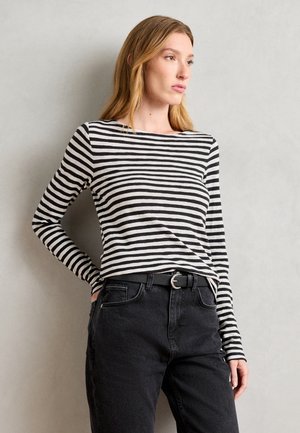 Haut à manches longues rayé noir et blanc, design ajusté, tissu léger, col rond, associé à un jean noir taille haute et une ceinture.