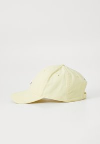Casquette de baseball en coton jaune avec une visière courbée, six panneaux et des accents brodés à l'avant et sur le côté. Sangle ajustable à l'arrière.